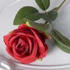 A vibrant red velvet artificial rose with green leaves on a white background.