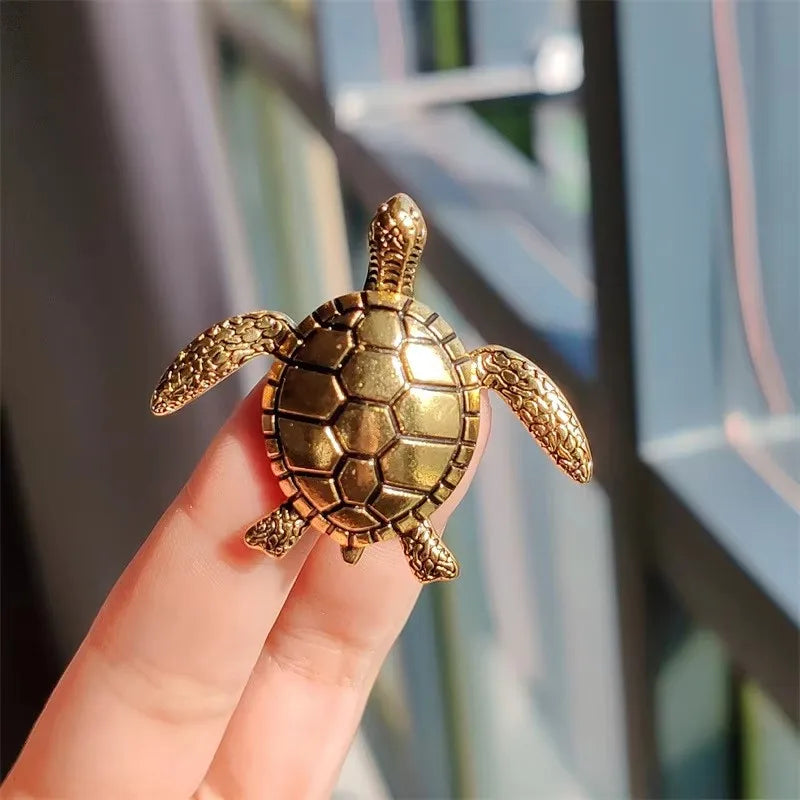 A golden vintage marine life brooch pin set shaped like a sea turtle held by a hand.