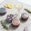 A collection of aromatherapy soy wax candles, including a glass candle holder and several decorative tins.