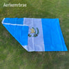 A large blue and white flag of Guatemala laid out on green grass.