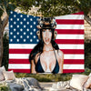 A woman wearing a helmet stands in front of a pink USA flag tapestry featuring red and white stripes and blue stars.