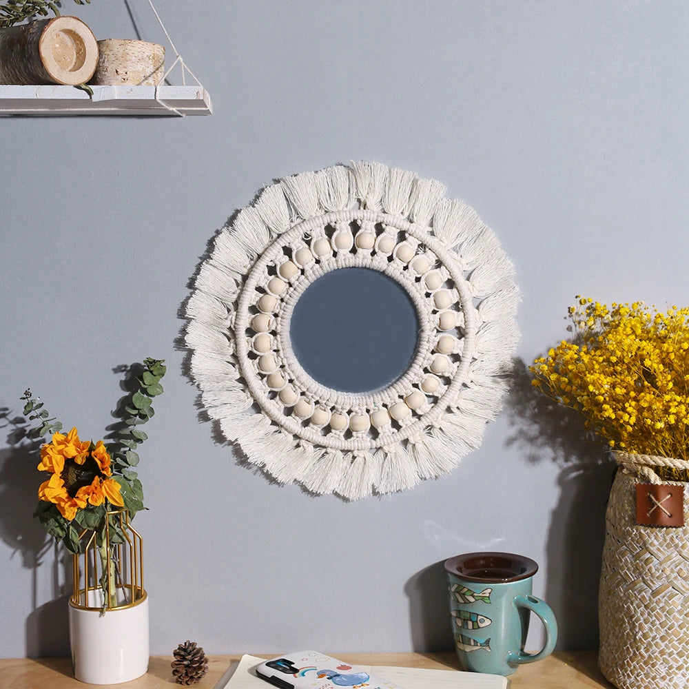 Miroir mural en macramé rond avec une frange blanche texturée accroché sur un mur gris.