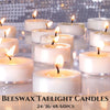A collection of white beeswax tealight candles with lit wicks arranged on a reflective surface.