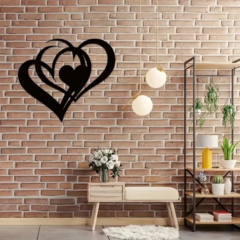 Black metal heart wall art with two intertwined hearts hanging on a brick wall above a wooden bench.