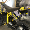 A yellow bicycle is shown with a black seat and digital camouflage vinyl wrap film applied to the frame.