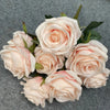 A bouquet of nine realistic pale pink and cream silk roses arranged on a gray background.