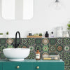 A white ceramic sink bowl is set against a green tiled backsplash in a kitchen or bathroom setting.