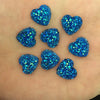 Eine Sammlung von zwölf blauen, herzförmigen Glitzer-Strasssteinen auf einer Hand.