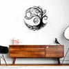 A black silhouette of a tree of life design mounted on a white wall above a wooden cabinet.