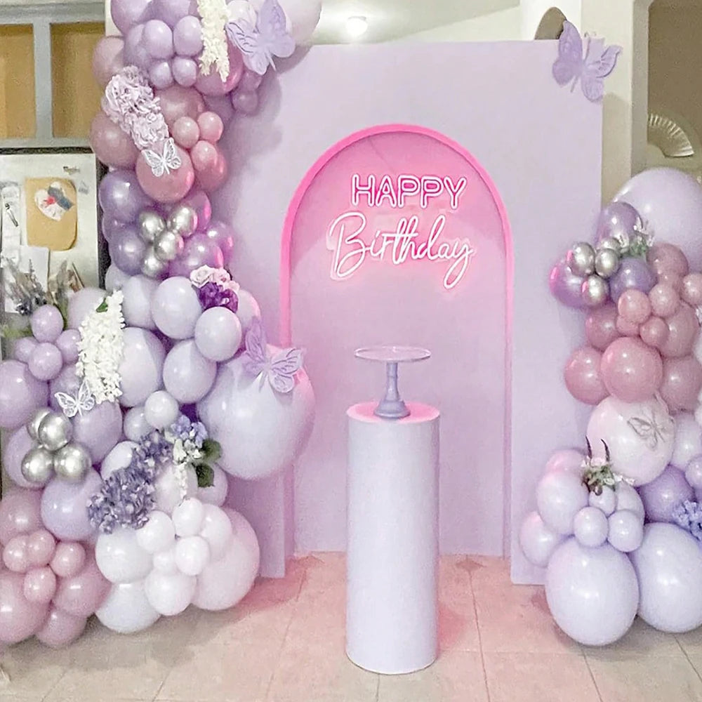 A pink and purple balloon garland arch decorated with balloons, flowers, and a butterfly motif for a birthday celebration bac