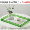 Grüner Acryl-Foto-Displayrahmen mit Glasgefäß, Grünzeug und weißem Dekor auf weißer Tischdecke.