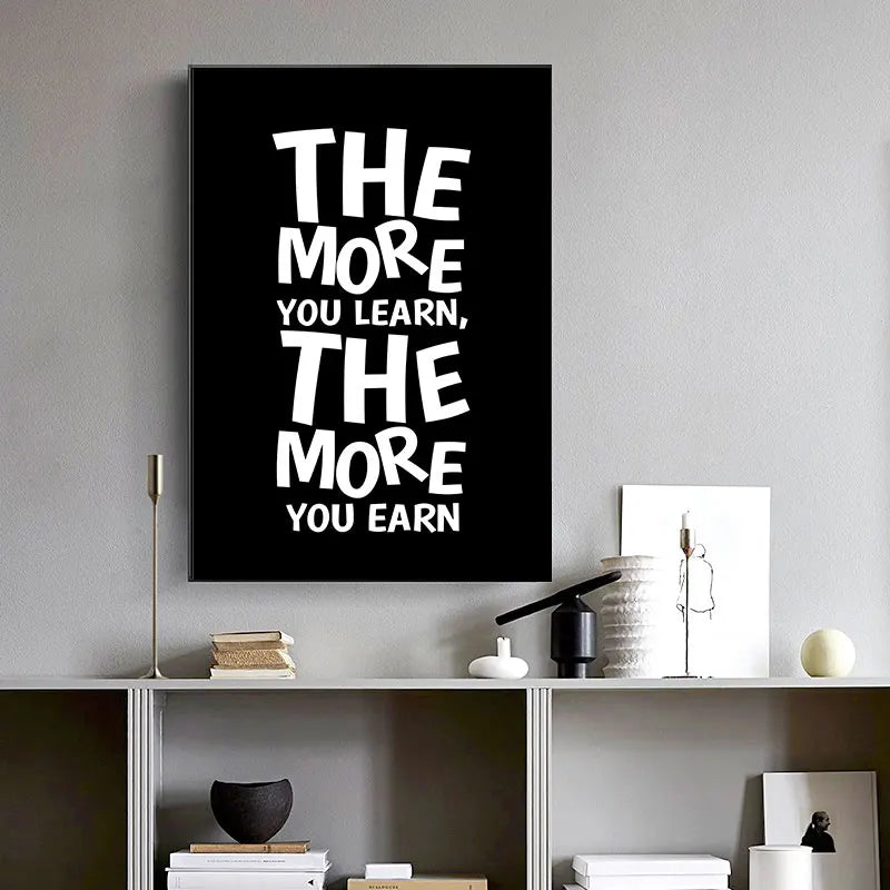 Black canvas art poster with white text that reads The more you learn the more you earn