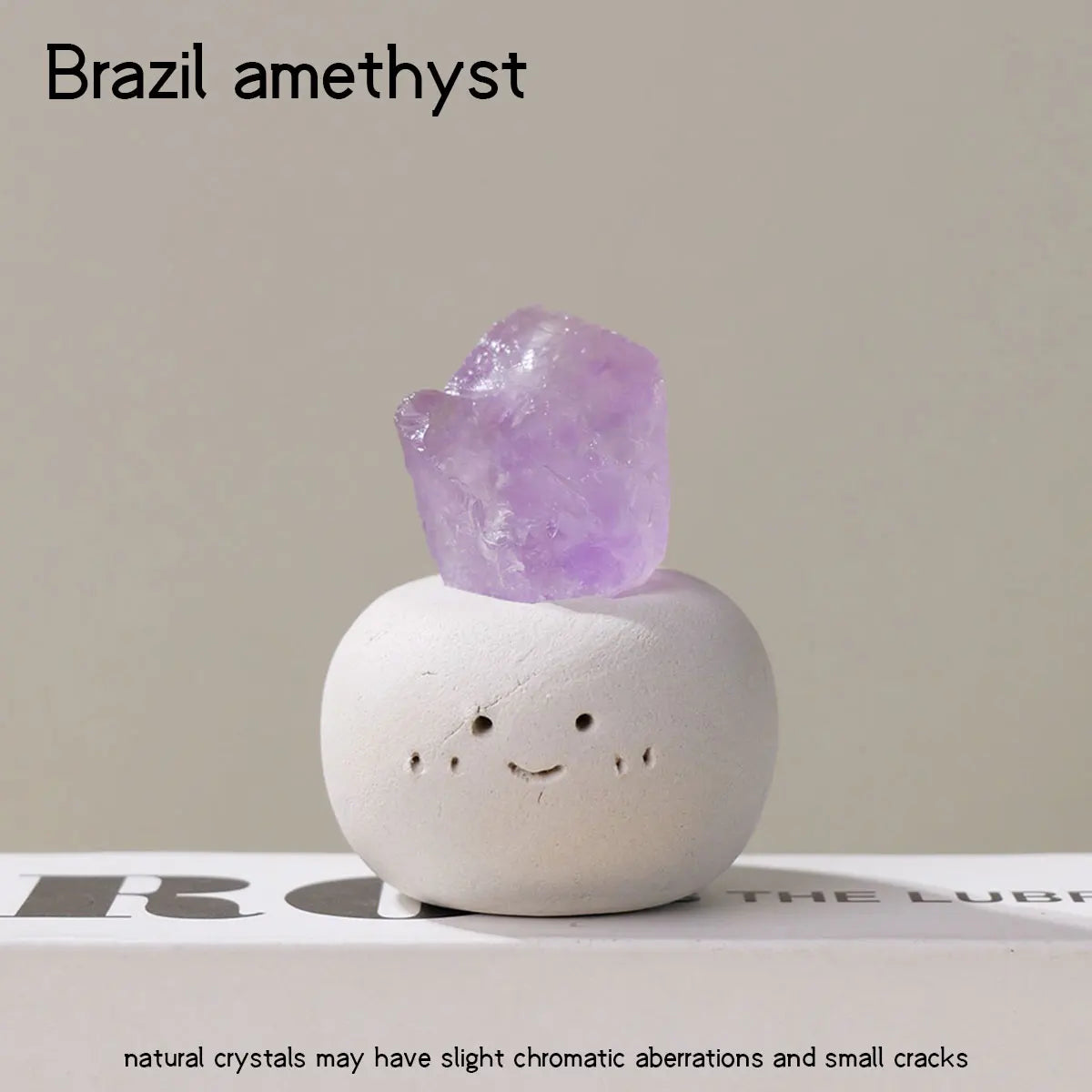 A clear purple amethyst crystal is set into a smooth, white bean-shaped decorative stone.