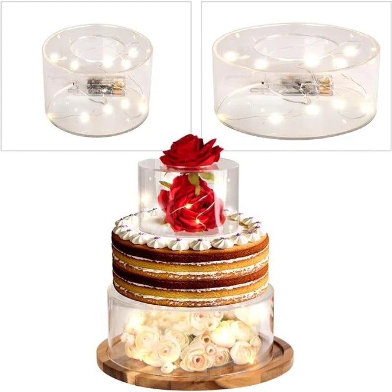 Clear acrylic cake stand display box with LED lights featuring a tiered cake decorated with red roses and white flowers.