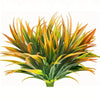 A vibrant artificial tall grass and tropical flower arrangement with green, yellow, and orange blades.