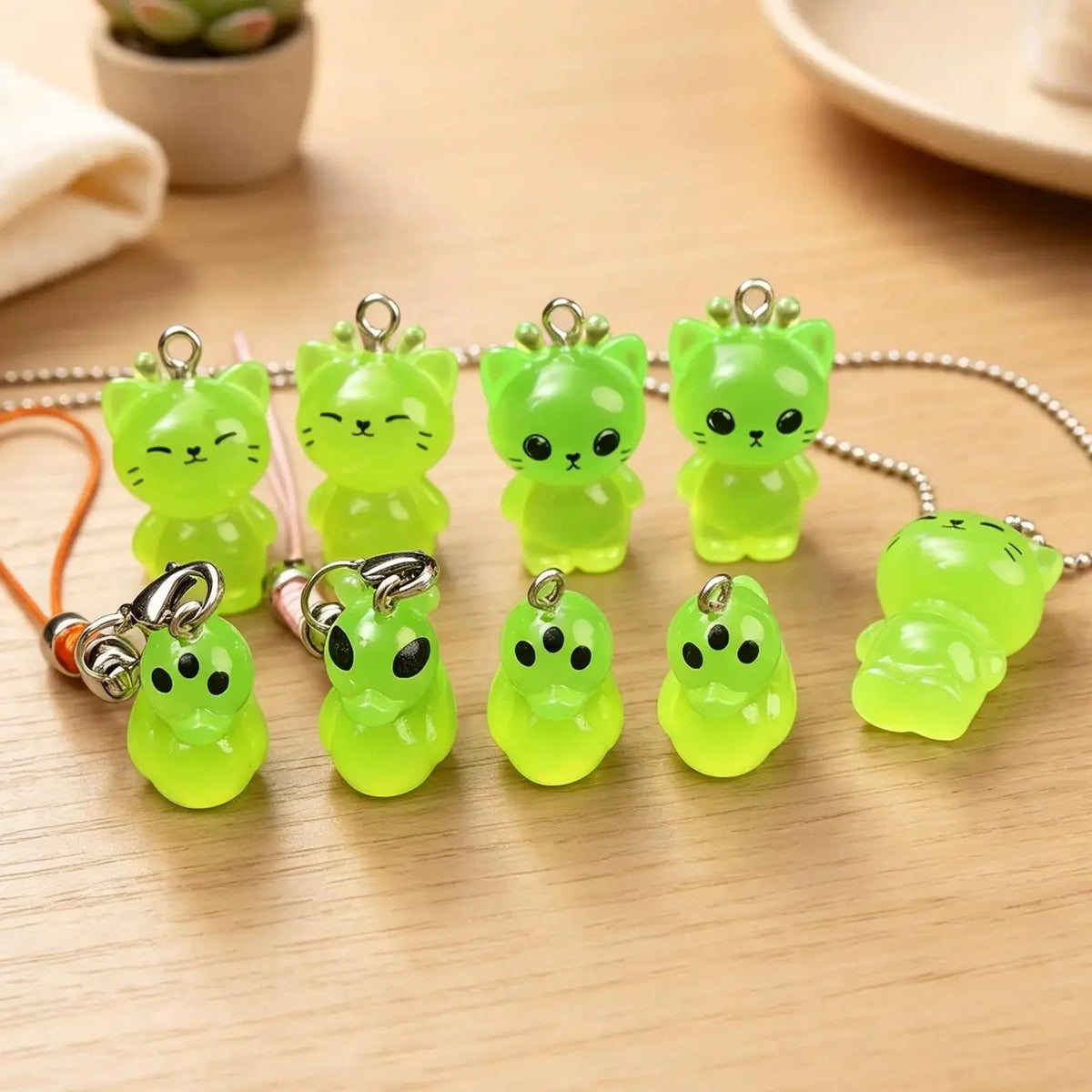 A collection of glow-in-the-dark resin charms shaped like alien cats and ducks on a beaded chain.