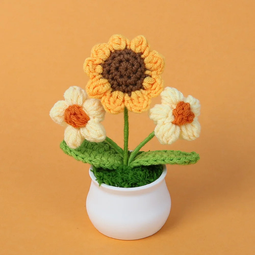 Hand woven crochet sunflower and daisy flowers in shades of yellow, orange, and brown potted in a white ceramic cup