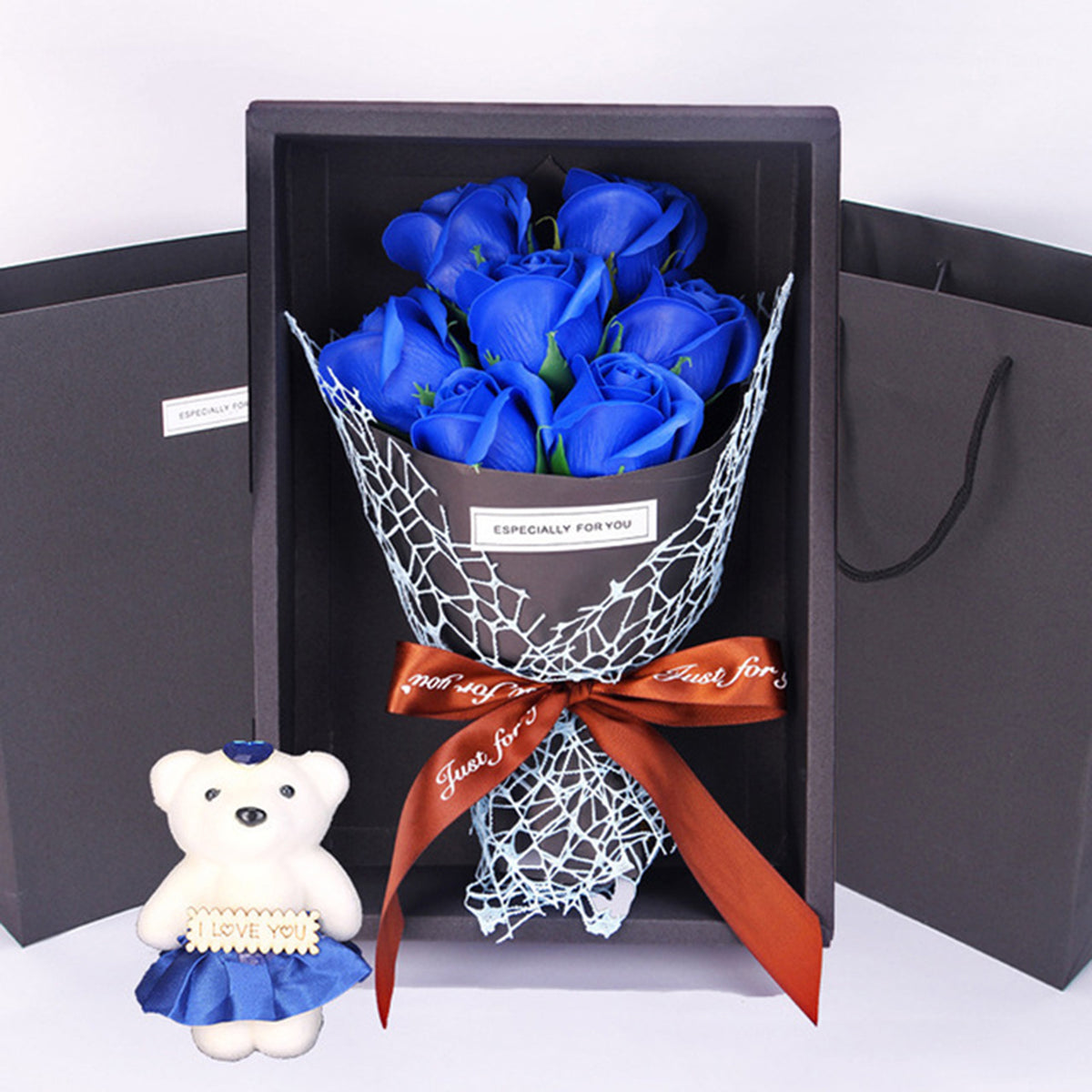 A gift box containing a bouquet of blue roses and a white plush bear.