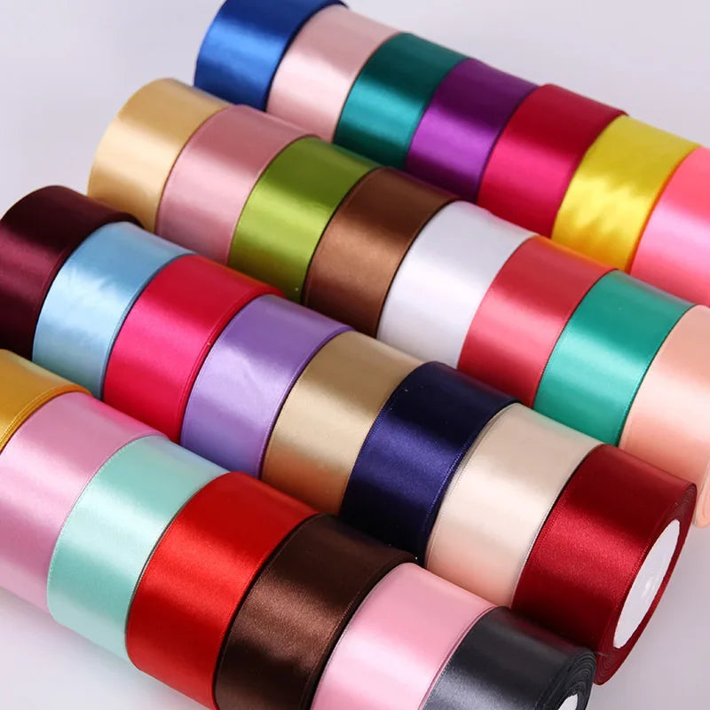 A collection of rolled silk satin ribbons in various colors including pink, red, green, purple, and blue.