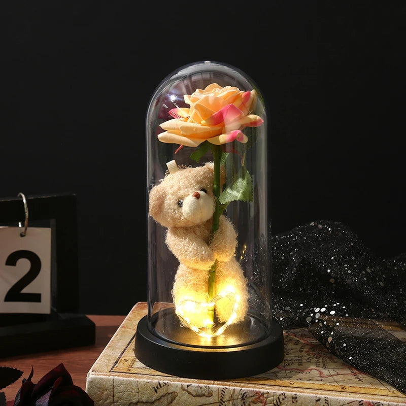 An eternal rose LED decorative flower is displayed inside a glass dome on a wooden surface.
