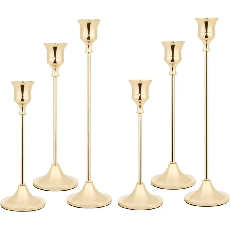A set of three ornate vintage metal candle holders with slender stems and flared bases.