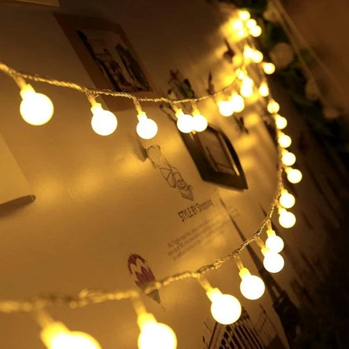 A close-up of battery-powered globe string lights with warm yellow bulbs strung across a surface.