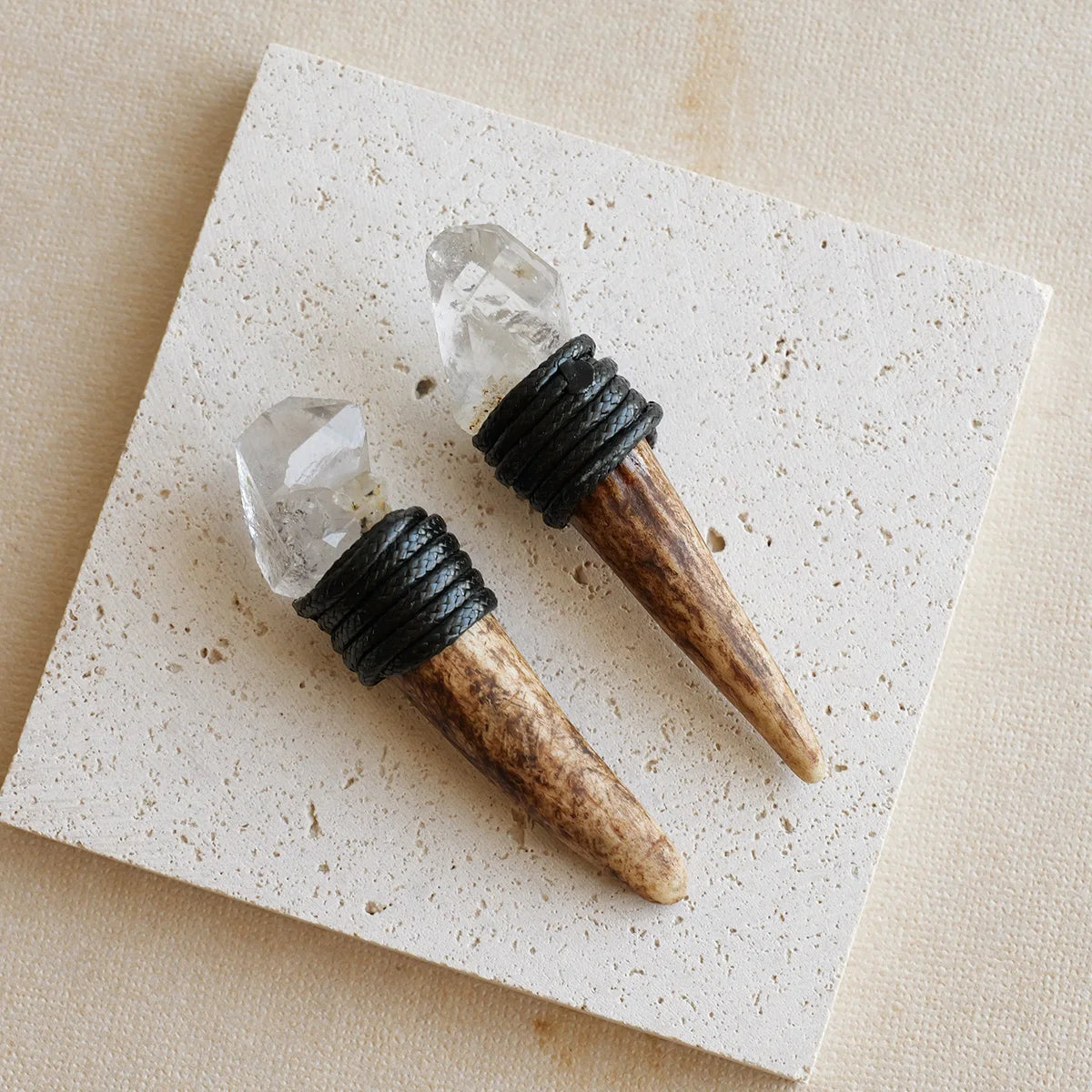 A natural crystal Herkimer scepter wand with a clear stone and black wrapped handle resting on a light background.