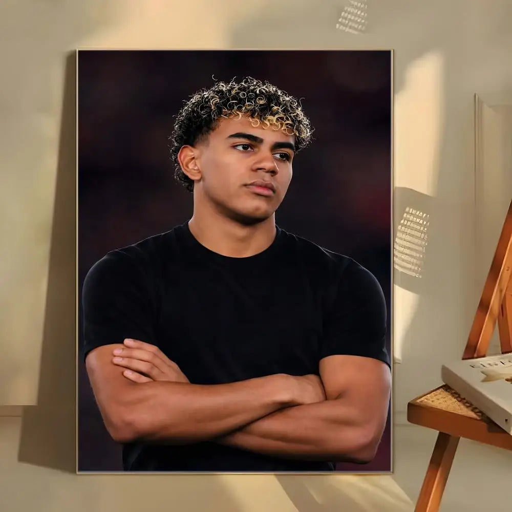 A portrait of Lamine Yamal with curly hair, wearing a black shirt, posed looking directly at the viewer.
