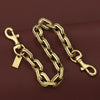 A gold and silver two-tone metal chain necklace with a pendant resting on a dark brown surface.