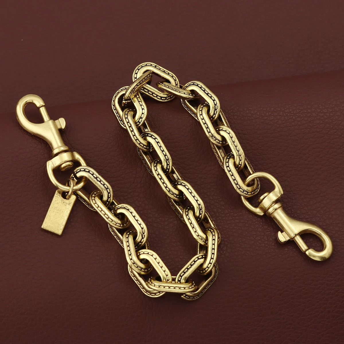 A gold and silver two-tone metal chain necklace with a pendant resting on a dark brown surface.