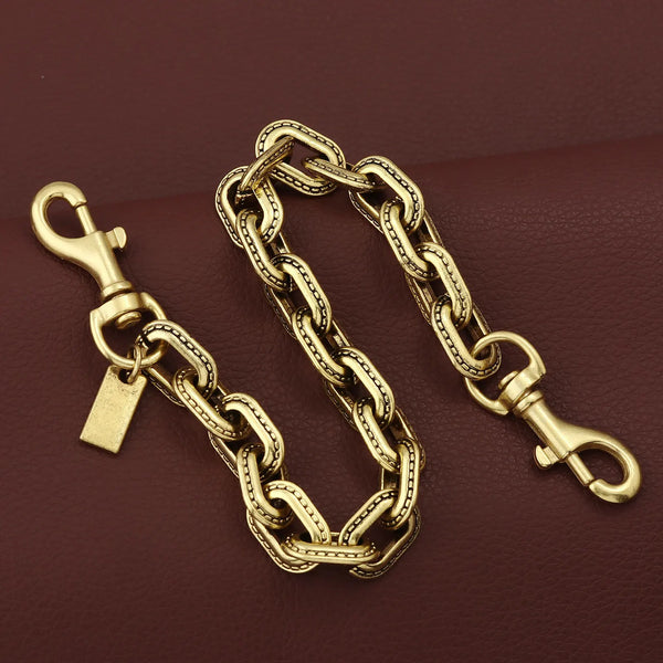 A gold and silver two-tone metal chain necklace with a pendant resting on a dark brown surface.