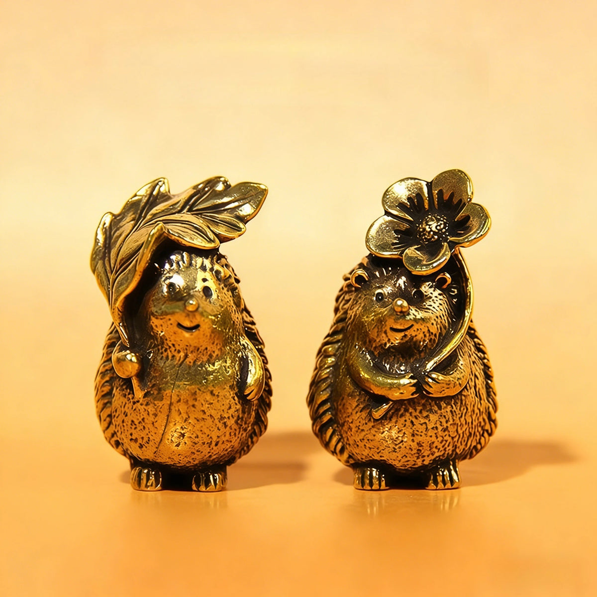 A small brass hedgehog statue with a flower on its head, sitting on an orange surface.