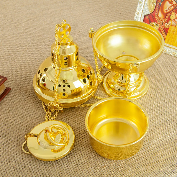 A gold-plated Orthodox censer with bells resting on a beige cloth.