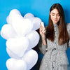 A woman holds a white heart-shaped latex balloon against a blue background.