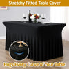 Black stretchy fitted table cover draped on a table with a vase of flowers and wine glass