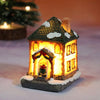 A miniature festive Christmas house night light with a thatched roof and warm LED glow, resting on a snowy base.