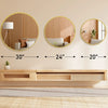 A wooden vanity setup featuring three round mirrors of decreasing size above a light wood shelf and a woven rug.