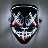 A black mask with glowing white LED lines forming an 'X' shape and a toothy grin, mounted on a wall.