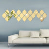 A set of ten gold reflective acrylic droplet mirror stickers arranged in a wavy line on a light blue wall above a modern sofa