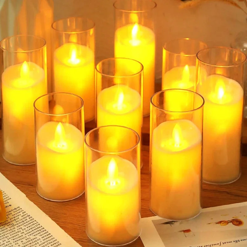 A collection of glowing yellow LED candles in glass holders arranged on a wooden surface.