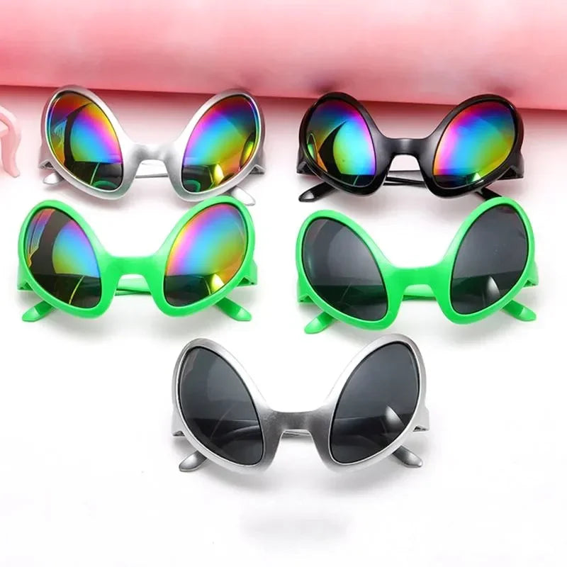 A collection of rainbow and colored sunglasses displayed on a pink background.