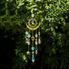 A hanging golden crystal wind chime featuring a crescent moon and sun design with various colored crystals and charms.