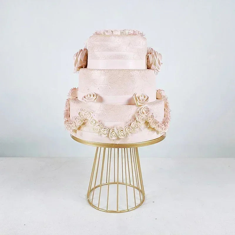 Mehrstöckiger rosa Kuchen mit Spitze und floralen Akzenten auf goldmetallischem Ständer.