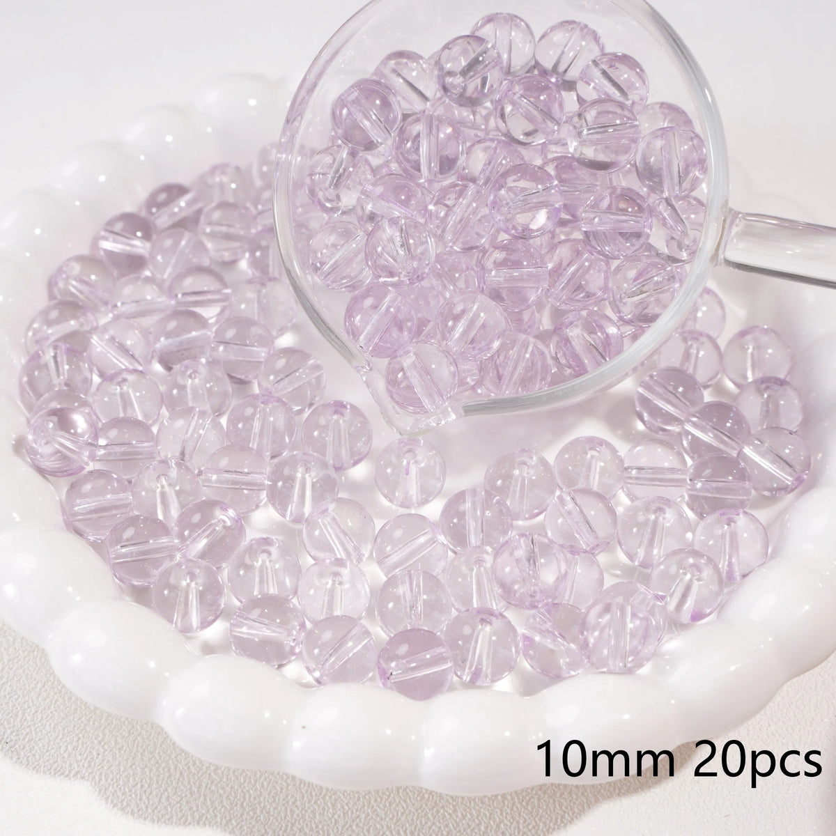 A clear glass dropper shows 20 small purple spacer beads scattered on a white dish.