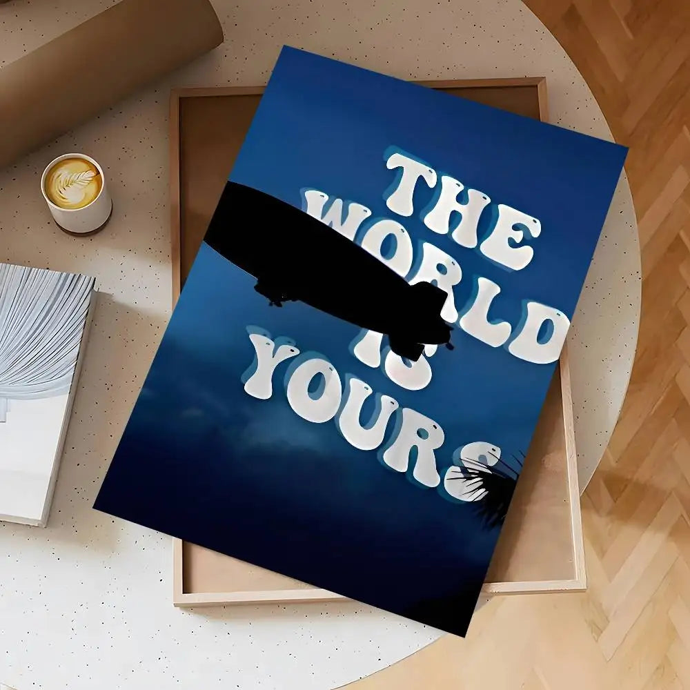 A dark blue poster featuring white text that reads The World Is Yours, displayed on a light wooden background.