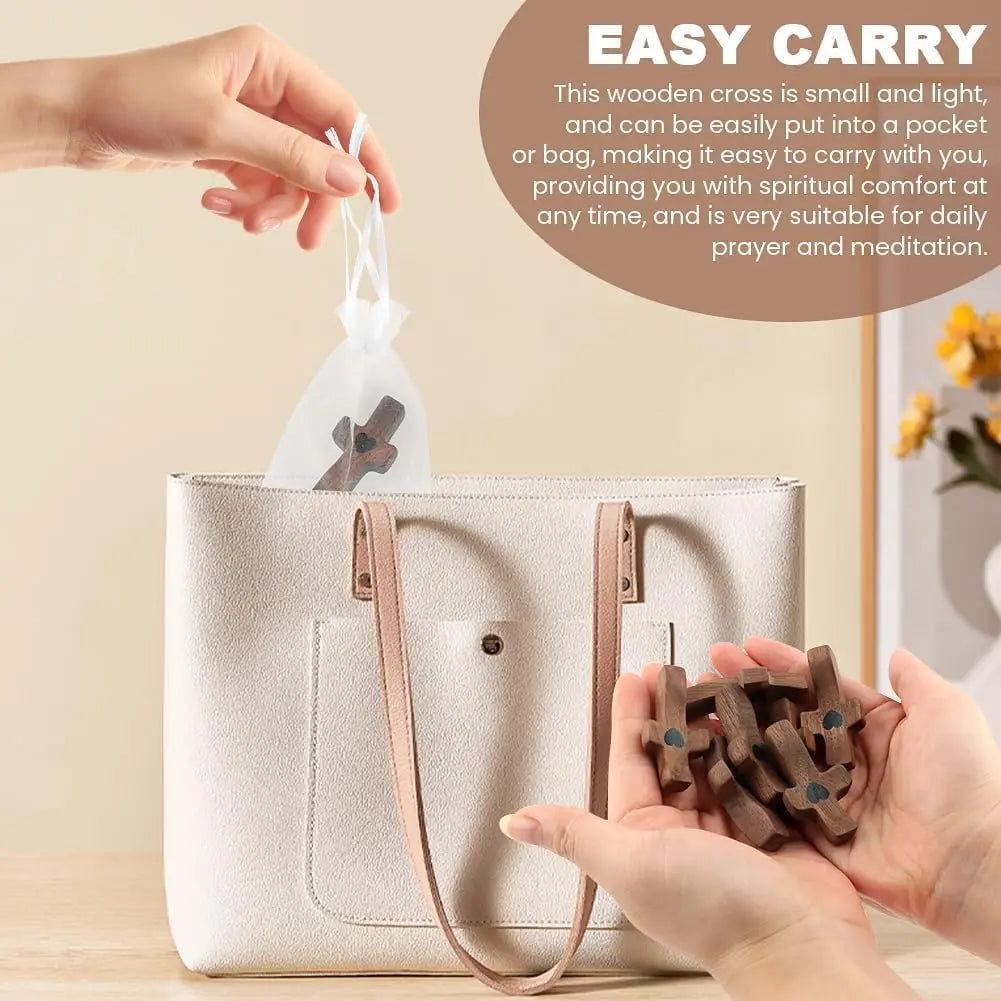 A hand places a small wooden cross into a pocket of a beige canvas bag.
