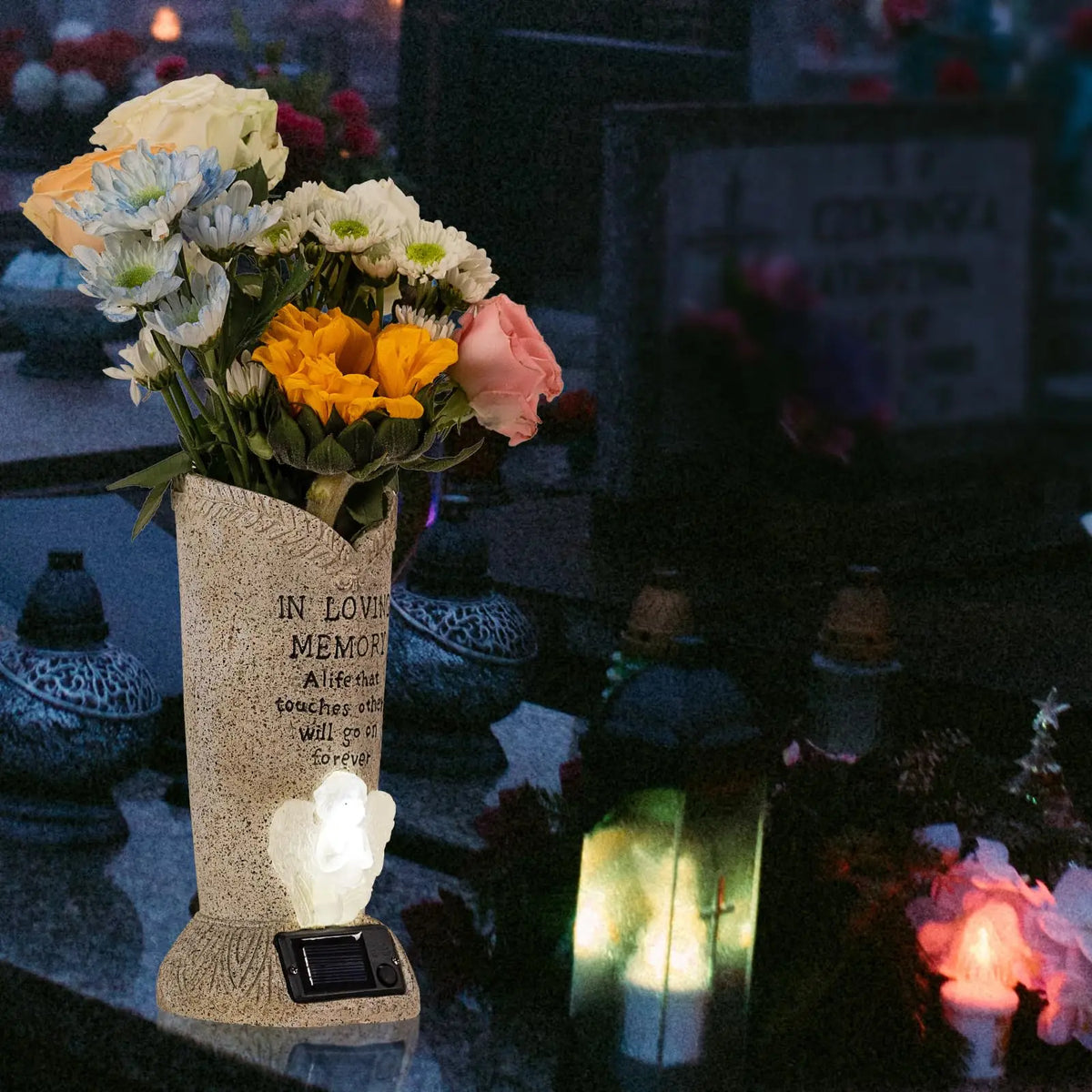 A stone vase holding white and yellow flowers with an LED light, set on a dark surface.