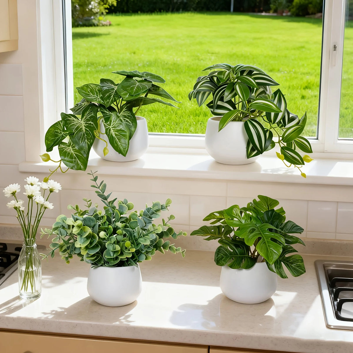 Several artificial green plants in white pots are displayed on a windowsill.
