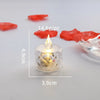 A small glass candle holder with a crystal tip and LED light, surrounded by pieces of red crystal.