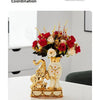 A pair of gold and white ceramic vases shaped like swans displayed on a white table.